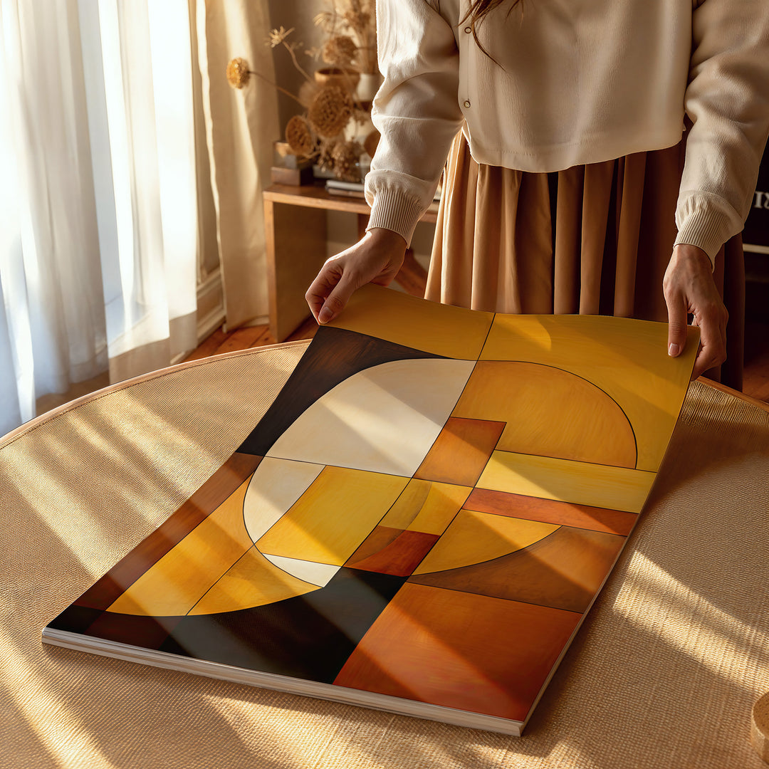 A rolled fine art print of 'Sun & Moon' being carefully handled, highlighting the rich amber, ochre, and deep brown tones. The luxurious giclée print captures the interplay of light and form, ideal for collectors and modern art enthusiasts.